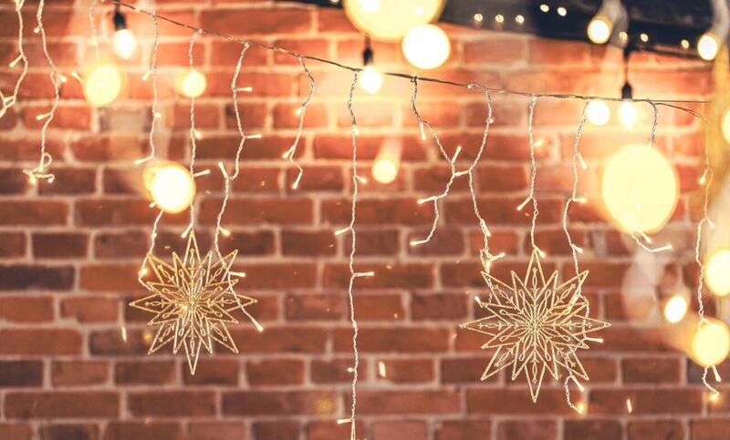 Guirnaldas de luces colgando de una pared de ladrillos en la decoración de la casa navideña por la noche